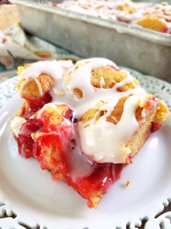 Cherry Danish Cake | An easy semi-homemade cake recipe dotted with cherry pie filling, drizzled with sour cream icing and topped with slivered almonds.