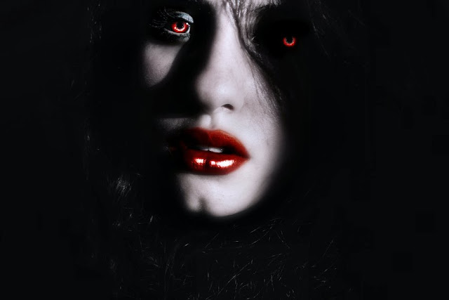 Imagen oscura del rostro de una hermosa vampiro, con los labios rojos al igual que sus ojos.