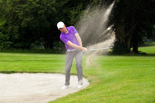 Golfer getting out of a bunker playing hazard