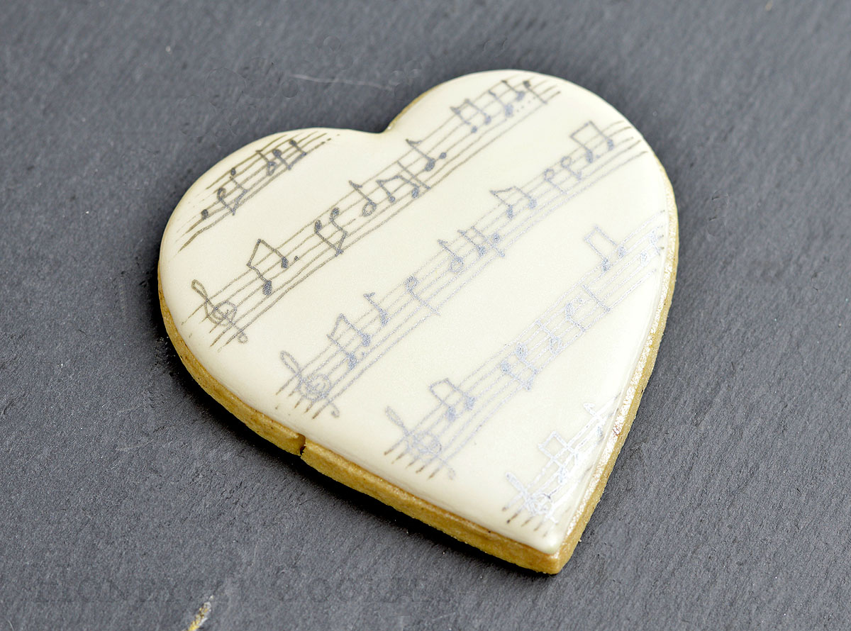 Musical notes hand drawn with edible pen onto heart shaped cookie, photo by Honeycat Cookies