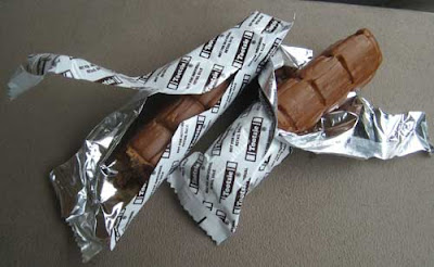 Tootsie Rolls opened to show that they are individually wrapped in silver mylar