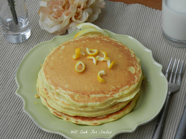 pancakes stacked up on a green plate with lemon zest on top 