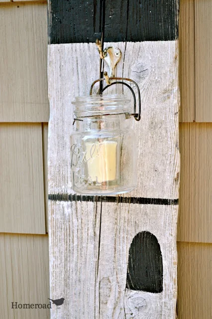 Large driftwood plank with hanging mason jar candle.