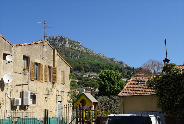 helles Haus mit gelben Fensterläden, Gebirge im Hintergrund, 