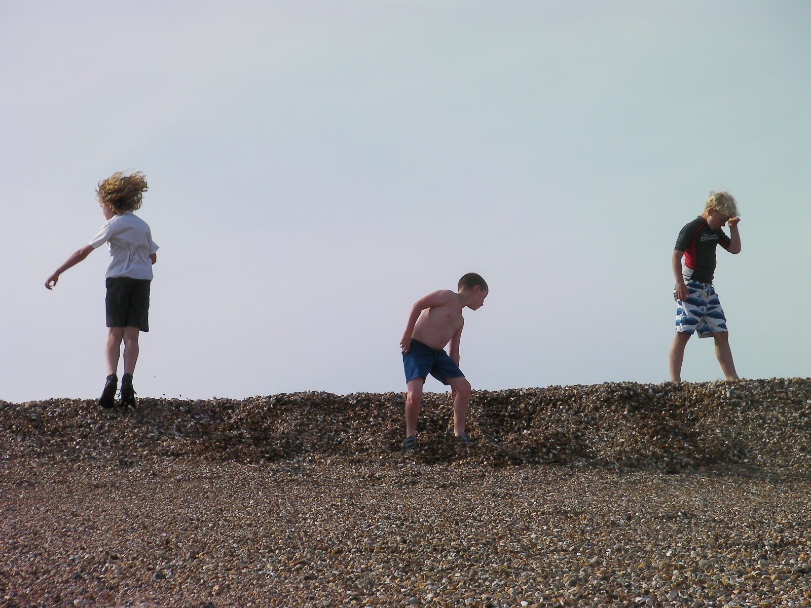 schoolfriends playing on the beach, silhouette shot southsea shingle beach at low tide