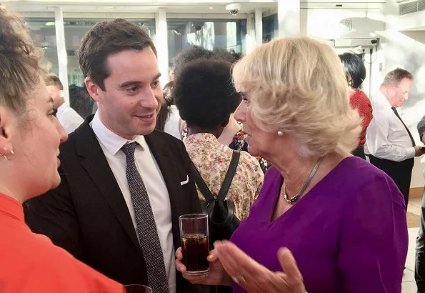 Camilla, the Duchess of Cornwall attended a literacy event for The Royal Society of Literature at the British Library. purple top and print skirt