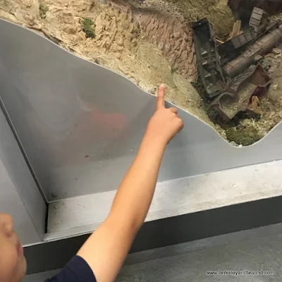 child points out wrecked train at Golden State Model Railroad Museum in Pt. Richmond, California