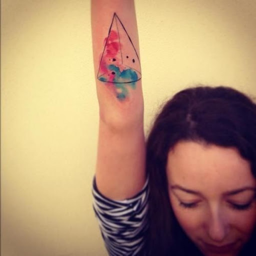 Um cone com uma aquarela de difamação é representado na parte inferior do utente do antebraço neste tatuagem.