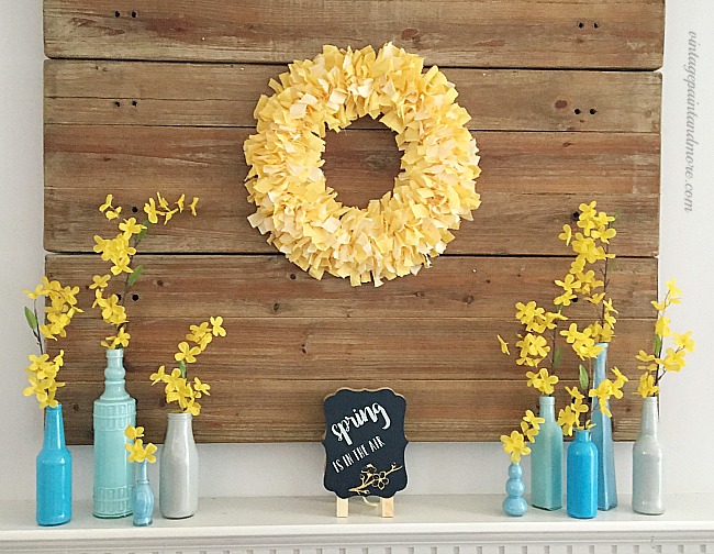 Vintage Paint and more - Spring mantel done with a yellow fabric rag wreath,  blue painted bottles with forsythia stems and a cute chalk board
