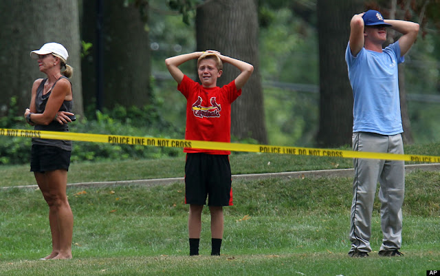 Emotional friends and neighbors stand outside the yellow tape as police detectives work the scene of a murder-suicide in a home in Glendale, Mo., on July 30, 2012.