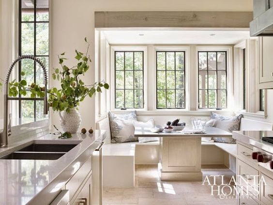 Gorgeous white farmhouse kitchen with black steel windows and banquette