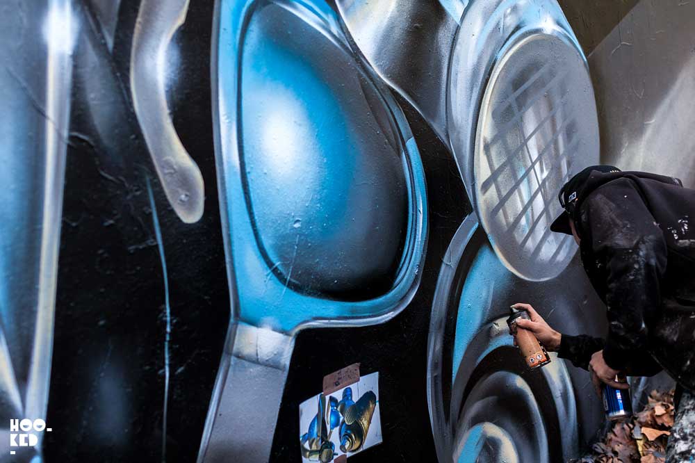 London street artist Fanakapan paints a mural in East London's Seven Star Yard car park.