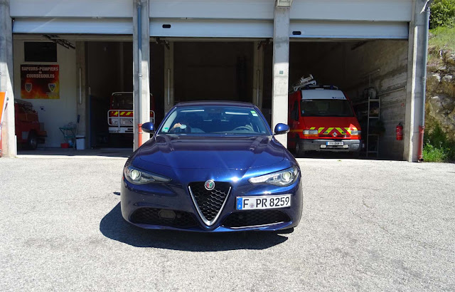 Blaue Alfa Romeo Giulia Super vor Feuerwehrautos in den Bergen