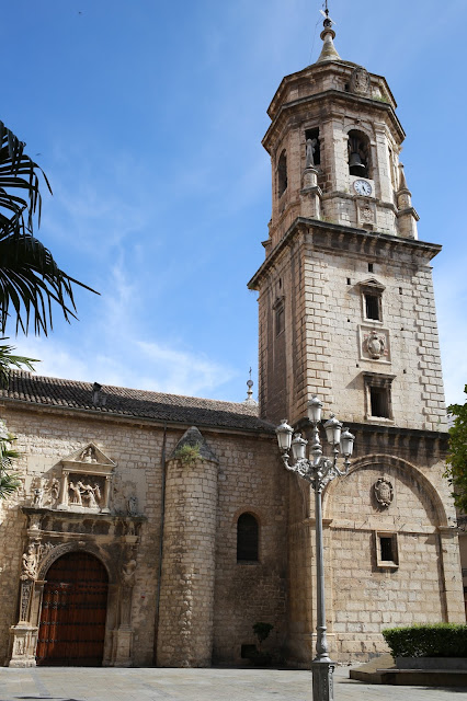 Fachada y campanario de una iglesia antigua desde una plaza de ciudad.
