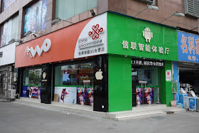 Store with China Unicom and Android signs plus some pillars with Apple logos
