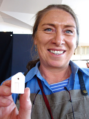 Woman holding up a tiny pottery house.