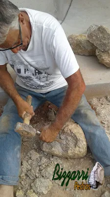 Bizzarri trabalhando, fazendo o corte das pedras moledo para fazer o revestimento de pedra na parede, com pedra moledo na cor bege com espessura de 15 a 20 cm.