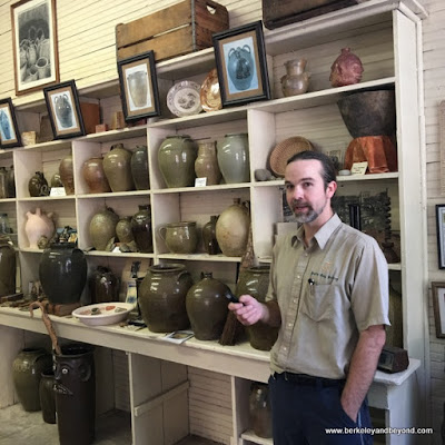 Master Potter Justin Guy in front of historic pottery collection in Old Edgefield Pottery in Edgefield, South Carolina