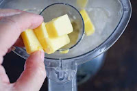 Adding chilled butter to food processor to make shortbread crust for pecan pie bars
