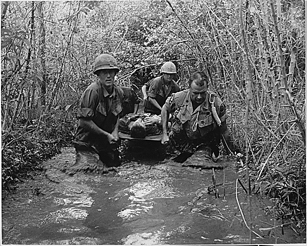 American soldiers carry a wounded comrade through a Vietnam Swamp. Photo by Paul Halverson, 1969. Image from The Veterans Hour.