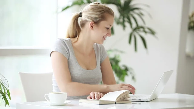 Beautiful young woman working on laptop showing a hot cleavage of her sexy boobs