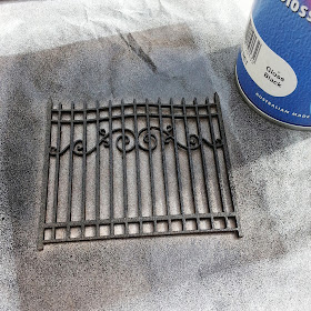 Spraypainted chipboard scrapbooking gate with a can of black spray paint next to it.