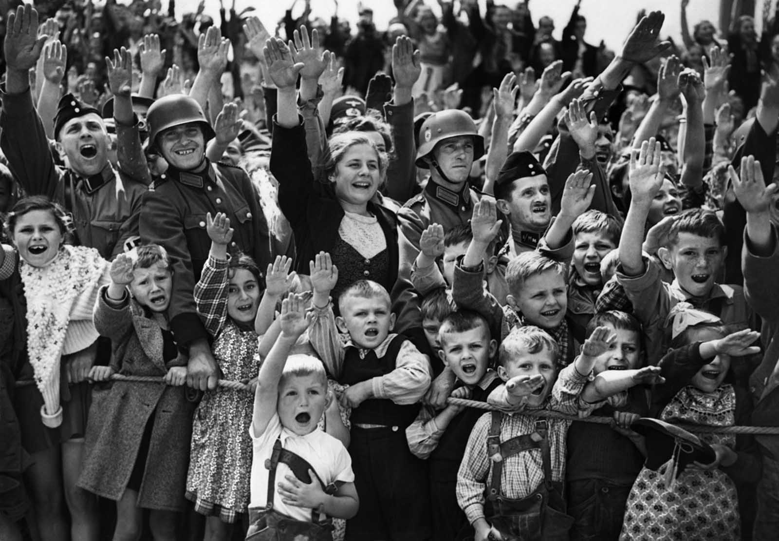 A crowd of women, children and soldiers of the German Wehrmacht give the Nazi salute on June 19, 1940, at an unknown location in Germany.