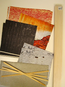 A selection of scrapbook paper sheets with distressed brick, plaster and wood patterns. A lenght of balsa wood and several lengths of dolls' house miniature skirting board.