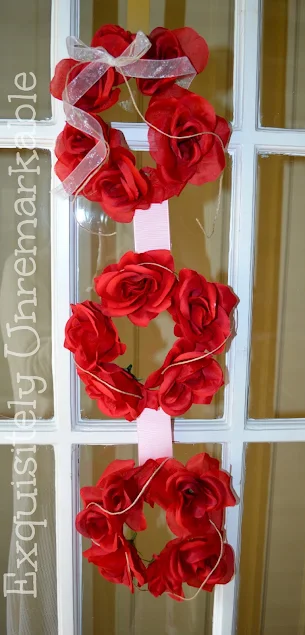Triple wreath of red roses and pink ribbon hanging on French Door