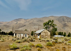 dilapidated shacks, sagebrush foreground, golden hills background 