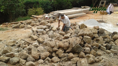 Bizzarri preparando as pedras moledo para iniciar o revestimento de pedra na parede da adega com pedra moledo.