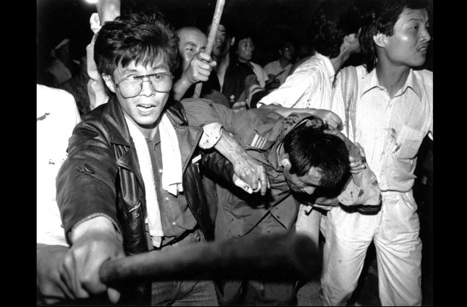 A captured tank driver is helped to safety by students as the crowd beats him, on June 4, 1989, in Tiananmen Square.