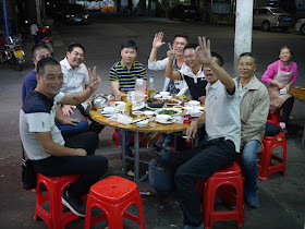 group of men eating and drinking at an outdoor table