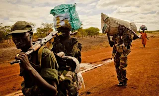 South Sudan Defense Forces soldiers and a woman carry their belongings along the road from Agok to Turalei South Sudan
