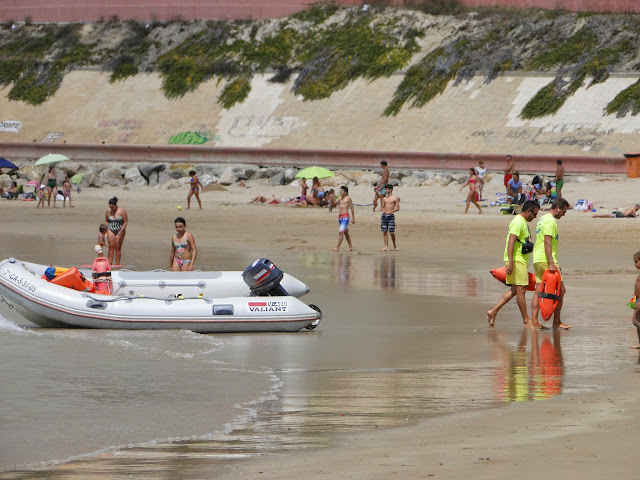 Barca y personal de salvamento de la playa en una playa de arena con mucha gente.