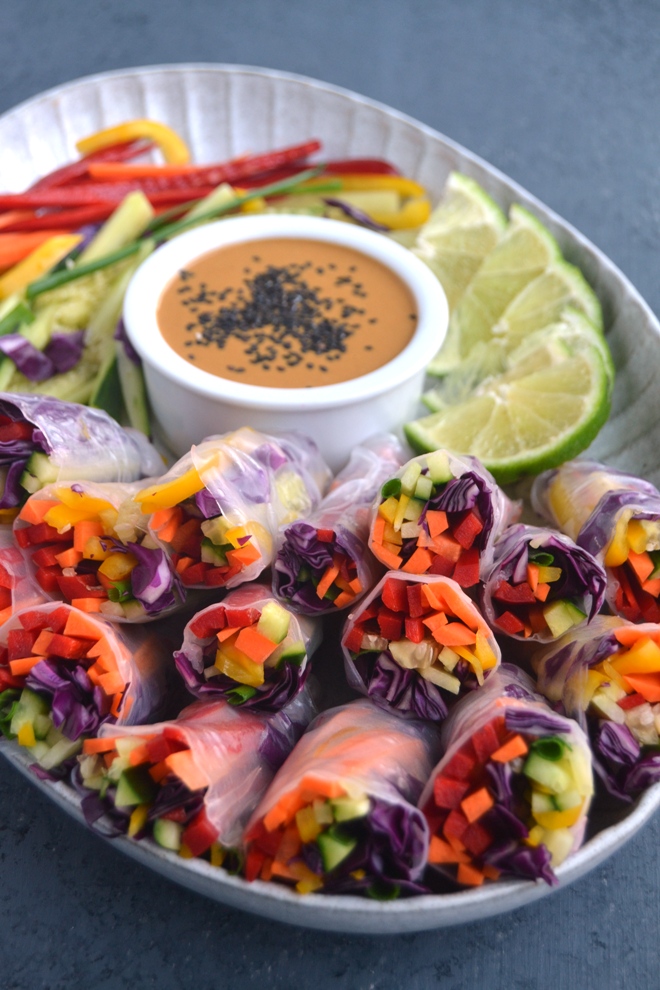 Rainbow Veggie Spring Rolls with Peanut Dipping Sauce are loaded with red pepper, carrots, yellow peppers, cucumber, green onion and red cabbage and dipped in an easy peanut sauce for the perfect appetizer. www.nutritionistreviews.com