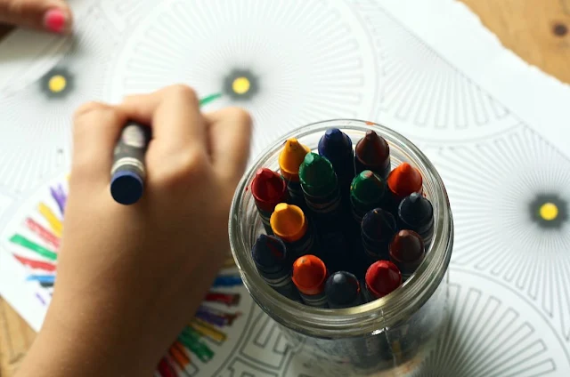 Child with good study habits using crayon to color book