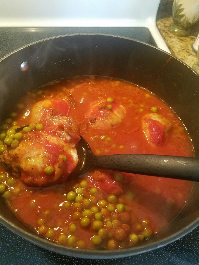 A big pot of sauce, chicken thighs, chicken legs and peas.
