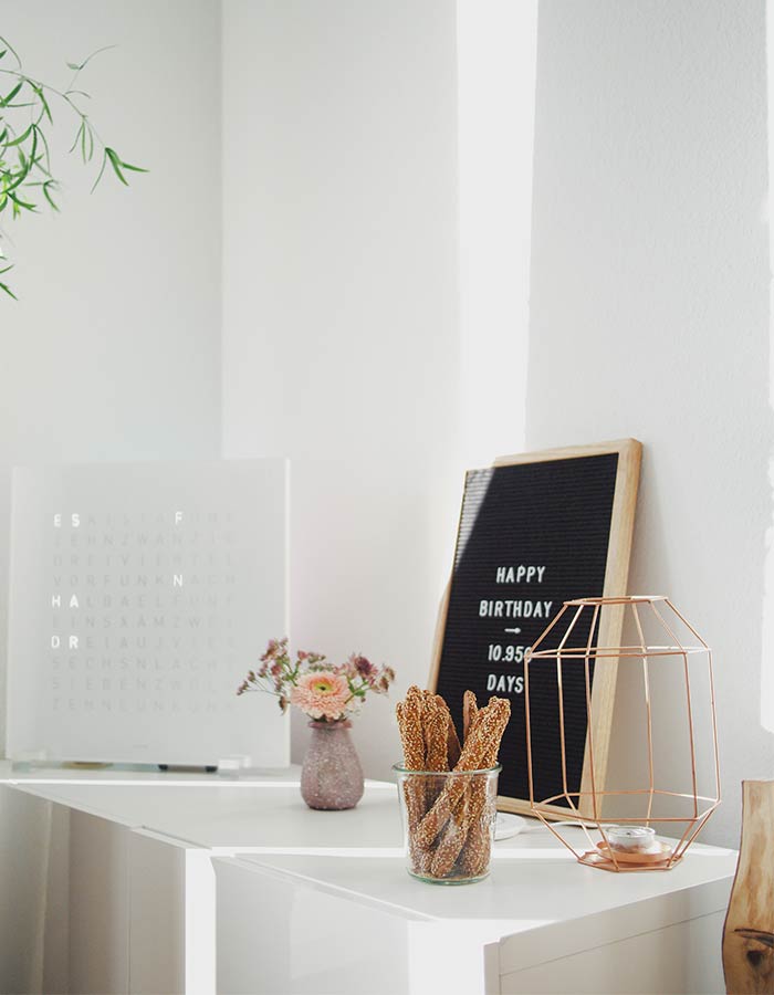 Decorando a cômoda do quarto com quadros, vela em castiçal geométrico rose gold e flores, com inspiração minimalista.