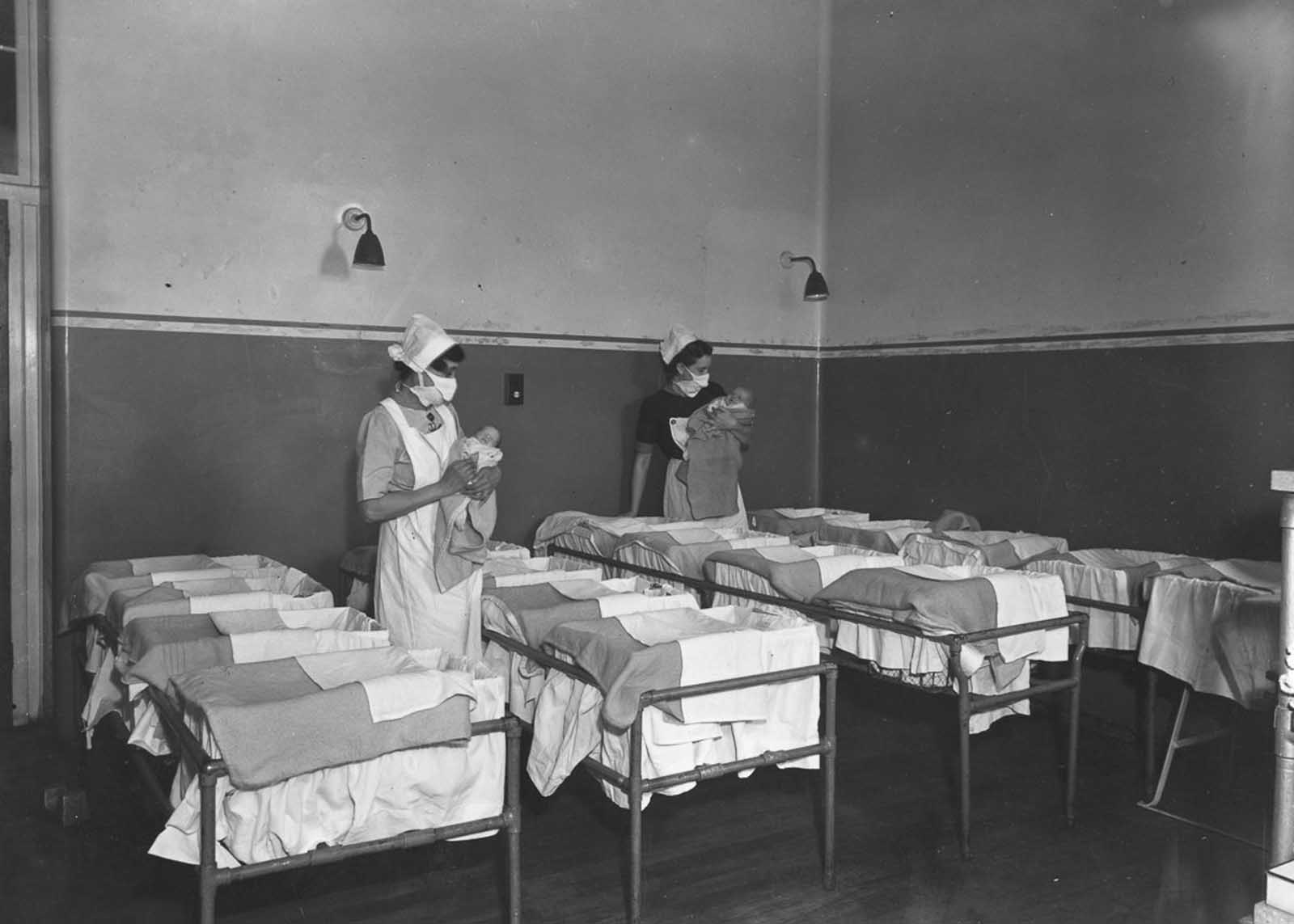 Nurses hold babies in a maternity ward at Guy's Hospital, London, 1947.