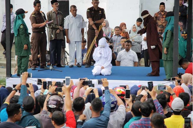 Tersangka PSK online di Aceh yang menjalani hukuman cambuk disaksikan ribuan warga. Tersangka PSK online di Aceh yang menjalani hukuman cambuk disaksikan ribuan warga.