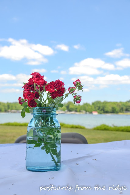 Red miniature roses in a pretty blue mason jar. Perfect for summer. Postcards from the Ridge.