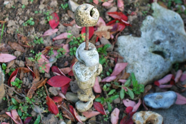 stones piled on a stick with autumn leaves around it