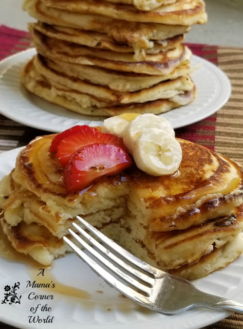 Serving of pancakes with bananas, strawberries and syrup