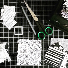 Flat lay of various black and white fabrics, scissors, pen and templates laid out on a cutting mat.