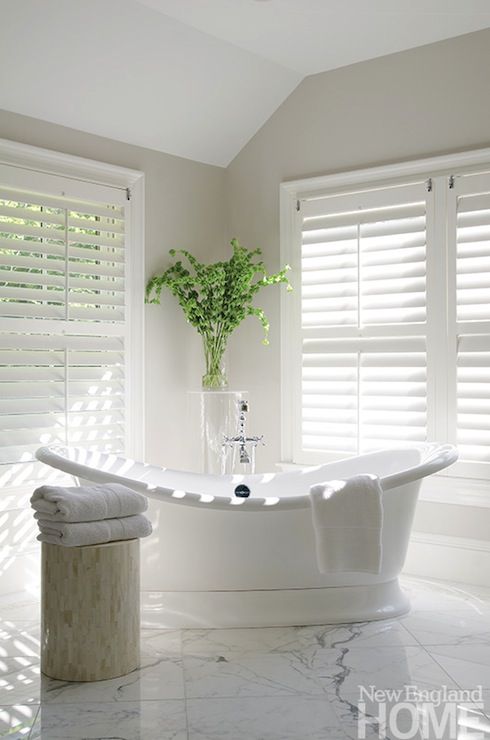 Beautiful bathroom with white plantation shutters and freestanding tub