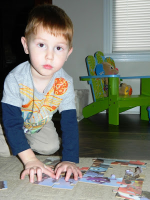 Young boy doing a puzzle on the rug