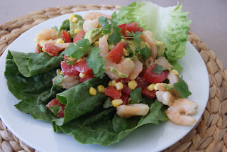Tomato, corn and shrimp salad served on a white plate.
