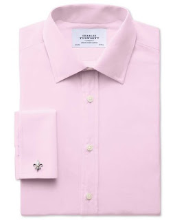 A folded up bright pink mens shirt on a white background. 