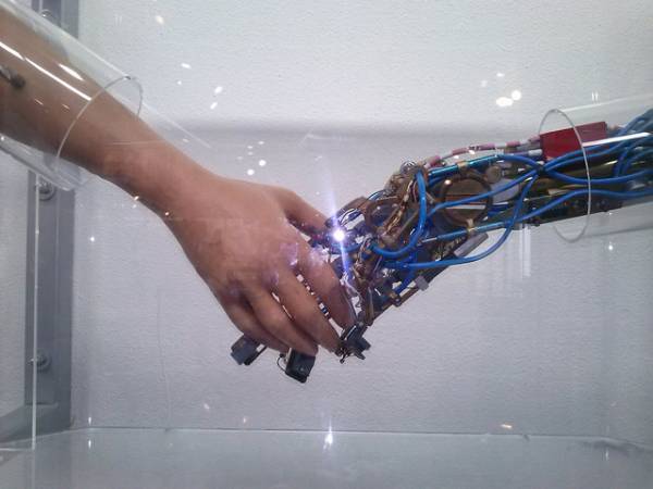 Una mano umana stringe una mano robotica